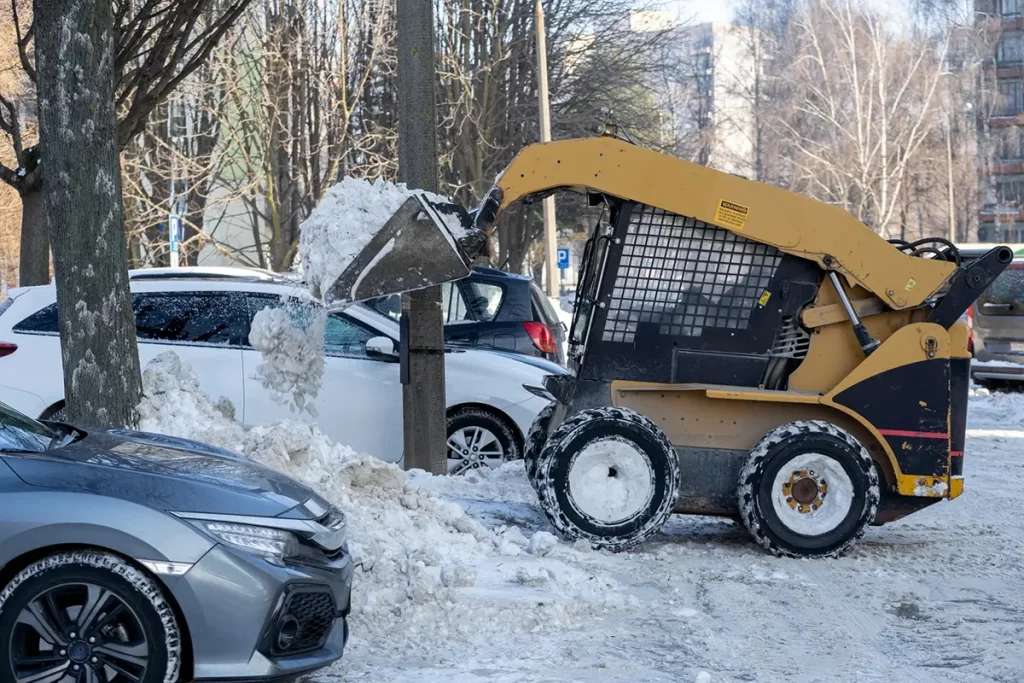 Snow plow clearing a commercial parking lot at sunrise